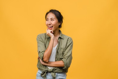 portrait of young asia lady with positive expression, arm crossed, smile broadly, dressed in casual cloth over yellow background. happy adorable glad woman rejoices success. facial expression concept.