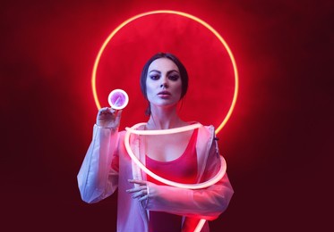 beautiful woman in futuristic costume on dark background. augmented reality, future technology, ai concept. red neon light.