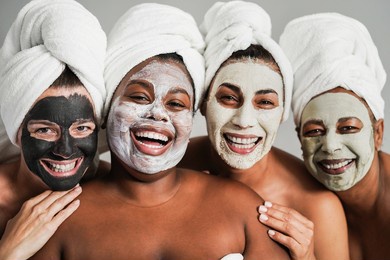 multigenerational women having fun wearing face beauty masks for skin care therapy - main focus on african girl face