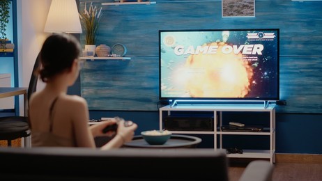 caucasian woman losing while playing video games holding controller sitting in living room for digital cyberspace reality indoors. person using virtual technology for entertainment