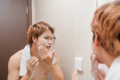 portrait of attractive young asian male wash his face in bathroom
