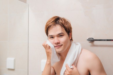 young man drying face with towel as part of daily hygiene routine