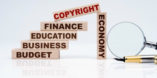 business and economy concept. magnifier, pen and wooden blocks with the text - business, budget, education, economics, finance and copyright