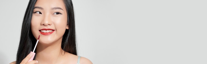 attractive and beautiful asian girl paint lips a pink lipstick, smiling make-up girl