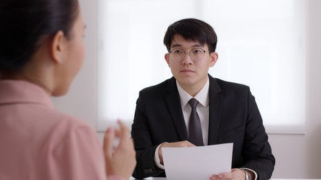 ceo man or hr boss in suit search new hire vacancy labor ask in cv career paper at office desk. asia sme owner or lawyer people listen or coach talk to worker agent, teach intern, advice bank loan.