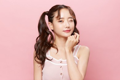 pink background portrait of a young asian woman with pigtails