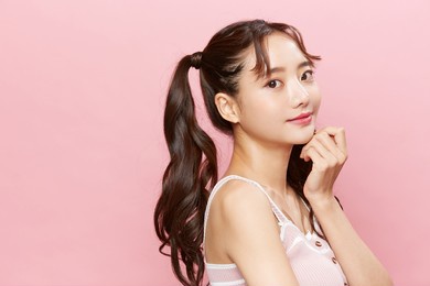pink background portrait of a young asian woman with pigtails