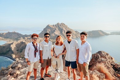 asian friends group in white shirt posing on a hill with an exotic view of padar island