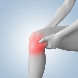 acute pain in a knee. woman holding hand to spot of knee-aches.