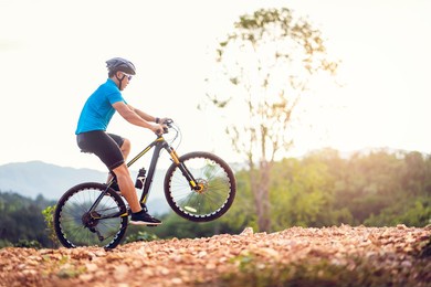 mountain bikes cyclist cycling, asian man athlete riding biking jumping on rocky terrain trail, extreme sport wear gear uniform helmet, exciting freedom outdoor sunset nature healthy active lifestyle