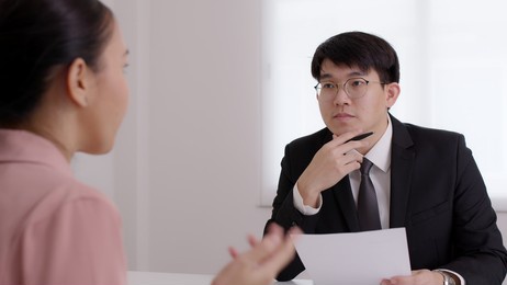 ceo man or hr boss in suit search new hire vacancy labor ask in cv career paper at office desk. asia sme owner or lawyer people listen or coach talk to worker agent, teach intern, advice bank loan.