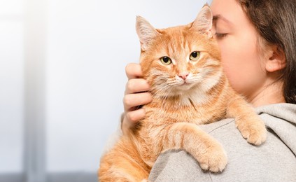 woman holding a ginger cat in her arms