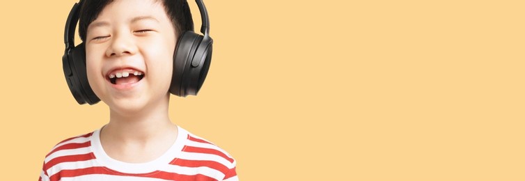 portrait of cute, smart and healthy  asian little boy in casual red white stripe shirt with headphone cheerful listening to music and sing along. happy kids, child development, eq, talented, fun.