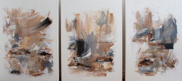 three contemporary abstract paintings on the art studio. nonfigurative abstract paintings of the same artistic series with colorful stains and strong brush texture.