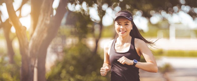 happy smiling adult asian woman jogging outdoor in the city park in sunshine beautiful summer day.  happy relaxed mature woman jogging to live an active and healthy lifestyle