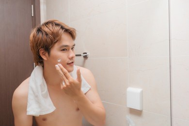 portrait of beautiful smiling healthy guy applying foam for washing on his face.