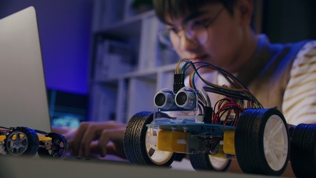 asian teenager doing arduino robot homework project in house