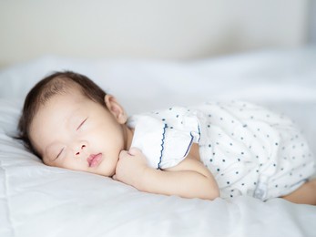close up adorable asian 3 months years old baby girl sleeping on white bed , newborn peace sleeping concept
