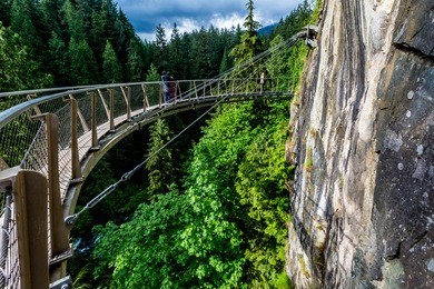 beautiful capilano cliff walk suspension bridge with tourists enjoying the view, in vancouver.