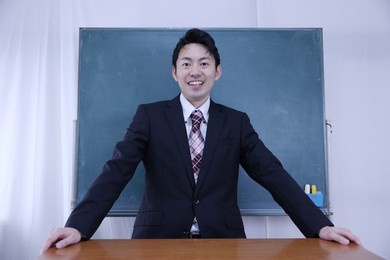 a male teacher in his 40s standing in front of a blackboard refreshingly