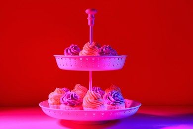 dessert stand with tasty cupcakes on dark color background