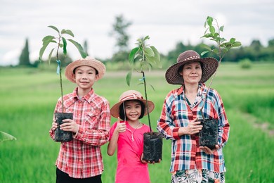 happy family people holding seeding of tree for planting to garden on organic green rice field background