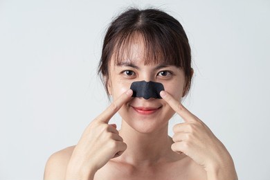 beautiful asian female model with mask charcoal deep cleansing nose pore strip on fresh clean skin. beauty and skin care treatment concept.