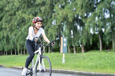 asian young sport woman riding bicycle in the evening in public park. beautiful athlete fit and firm girl in sportswear wear helmet, exercise by cycling workout for her health care wellness and fresh.