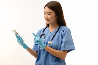 portrait of young asian female doctor holding mobile phone, with stethoscope and gloves, isolated on white background, health mobile application concept