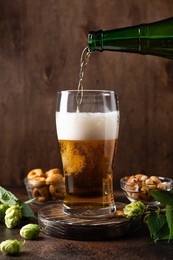 pouring fresh beer from bottle into beer glass. brewed and crafted quality product on wooden rustic background. vertical image