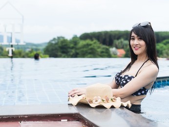 portrait beautiful young asian woman relaxes around the outdoor swimming pool in a hotel resort, holiday concept.