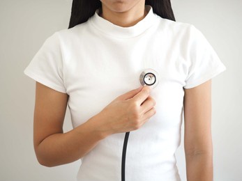 asian woman checking heart beats with stethoscope. closeup photo, blurred.