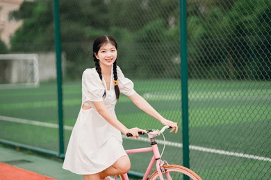 female college students push bicycles