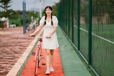 female college students push bicycles