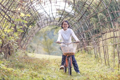 smile teenage girl with glasses on a bike in summer park outdoors