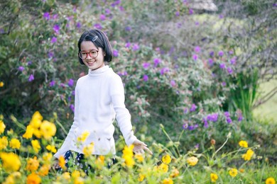 happy smile asian teen girl with glasses walks in the autumn flowers park