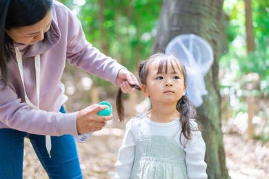 a mother spraying her child with insect repellent