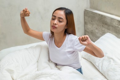 young asian beautiful woman stretching happy and relaxed after wake up feel fresh at home
