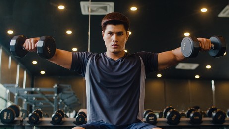 young athlete asian guy exercising doing lifting dumbbell fat burning workout in fitness class. sportsman recreational activity, functional training, people working out, healthy lifestyle concept.