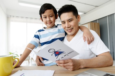 i love you, dad. asian happy family son surprise, made a greeting card my hero for daddy on father's day. conecept warm love bond