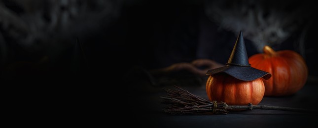 the mystical room of the witch. a decorative photo for halloween with a hat, pumpkins and a broom. banner in black and orange colors close-up.