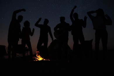 group of friends having party near bonfire at night. camping season