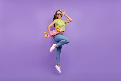 full length body size view of nice cheerful girl jumping listening pop dancing with skate isolated over purple violet color background