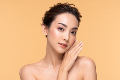 beautiful asian young woman touching soft cheek smile with clean fresh skin happiness and cheerful with positive emotional,isolated on beige background,beauty cosmetics and facial treatment concept