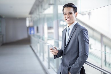 young asian business man smile holding smart phone at office area,man smart business concept.