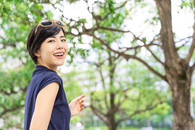 young asian woman walking in green street.