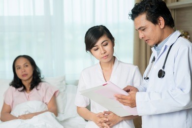 serious doctor and his assistant discussing symptoms of the disease