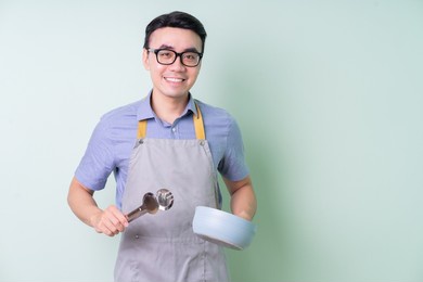young asian man wearing apron posing on green background