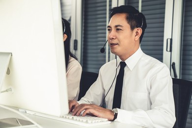 businessman wearing headset working actively in office . call center, telemarketing, customer support agent provide service on telephone video conference call.