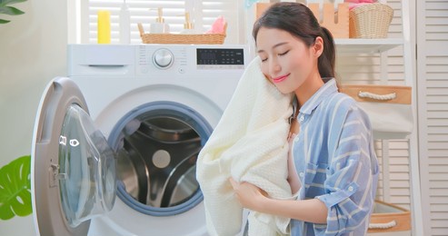 asian housewife take clothes from washing machine happily at home